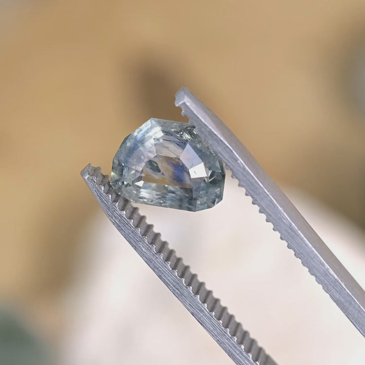 Loose 2.11 carat heated blue teal sapphire from Montana turning in natural light, revealing subtle shifts between blue and green tones in the tablet cut.