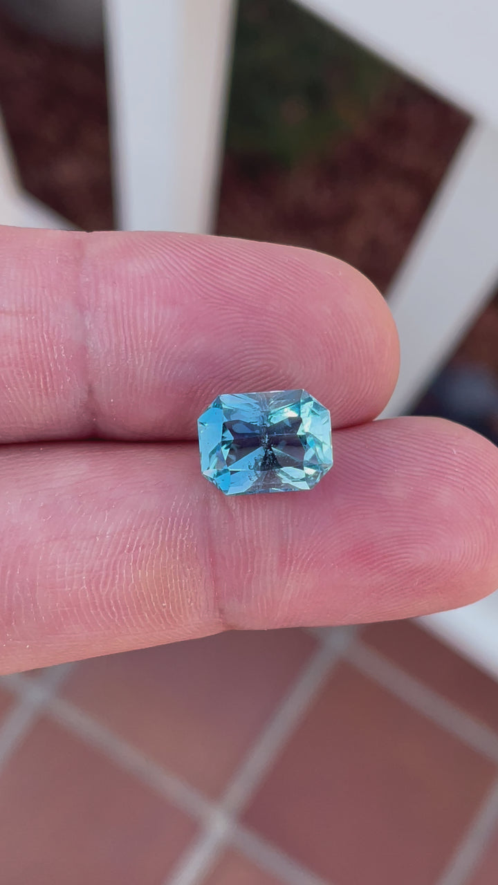 Detailed presentation of a 4.63-carat aquamarine from Nigeria, showing off its octagon radiant cut and mesmerizing double blue color. The video captures the gemstone under various light settings to demonstrate its exceptional clarity and captivating sparkle.