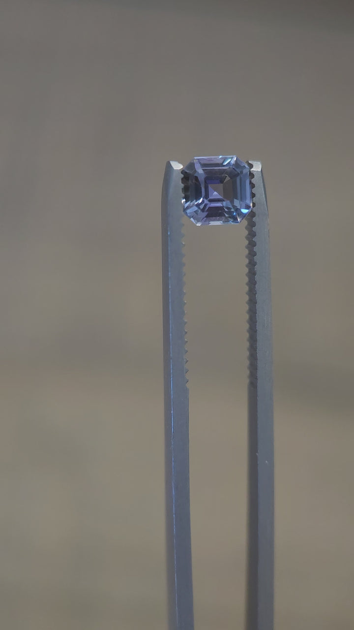 Close-up video of a 1.10 carat Asscher cut Tanzanite gemstone, featuring teal, blue-green, and purple hues, rotating to showcase its brilliance and precision cut.