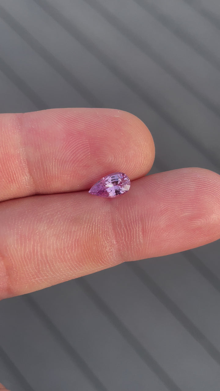 Detailed examination of a 1.54-carat purple sapphire in pear shape, rotating to showcase the stone's high-quality cut and vibrant color. This natural, untreated Sri Lankan gemstone offers a glimpse of its unique beauty in motion.