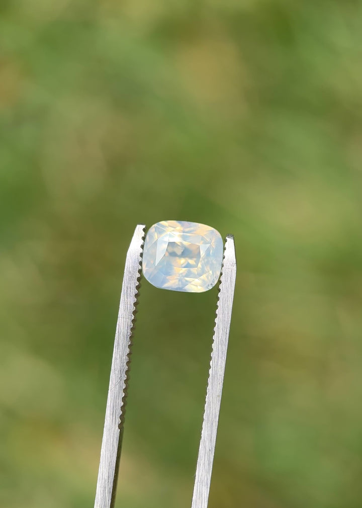 Rotating video of 3.01 carat opalescent white sapphire from Sri Lanka, showing precision cushion mixed cut facets and gentle internal shimmer under natural daylight.