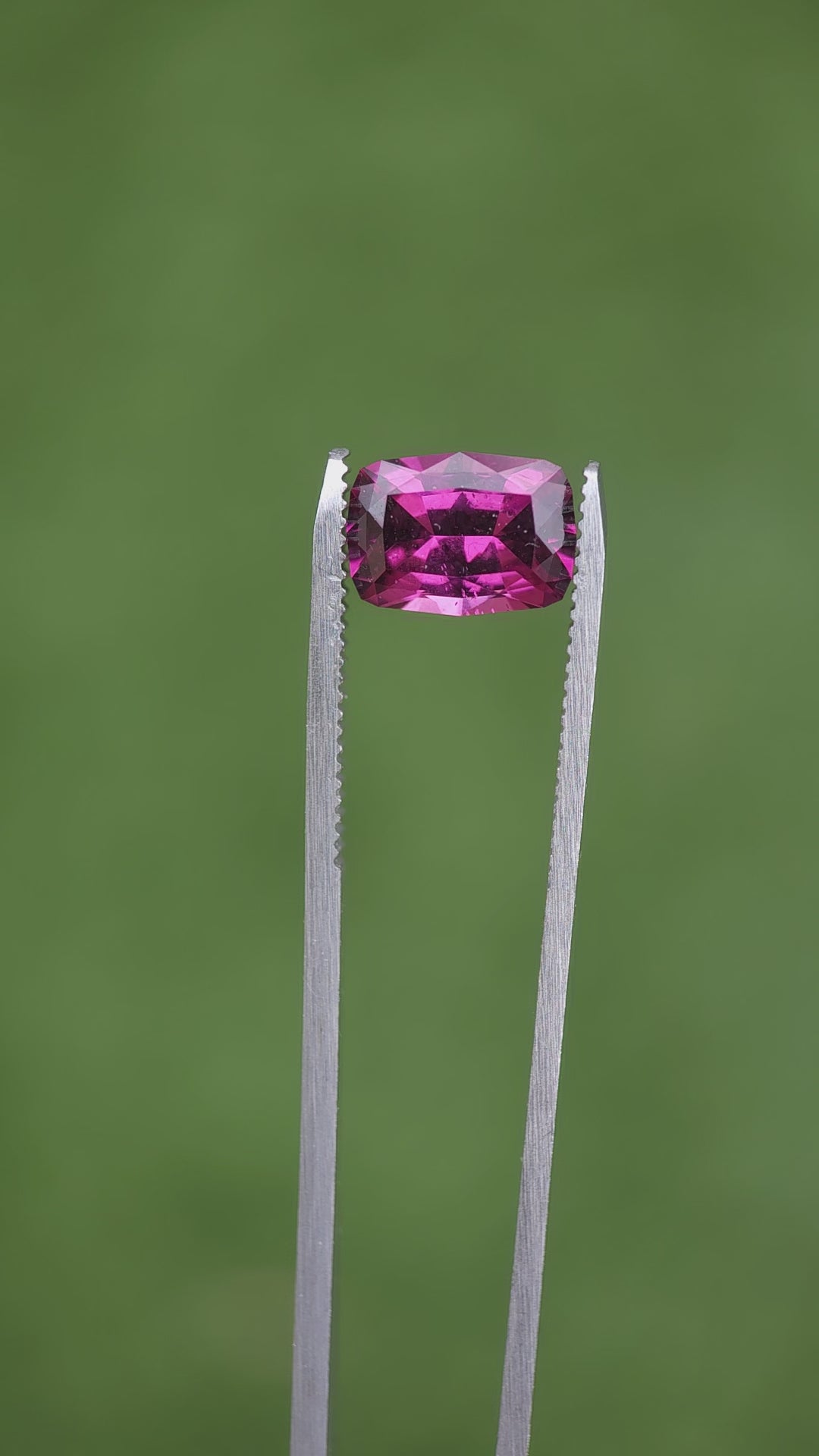 Video demonstration of a 4.29-carat garnet with a geometric modified cushion cut, capturing its vivid purple, pink, and red colors under various lighting conditions. The garnet, originating from Mombo, Tanzania, is displayed in its natural, untreated state, highlighting its unique clarity and color richness.