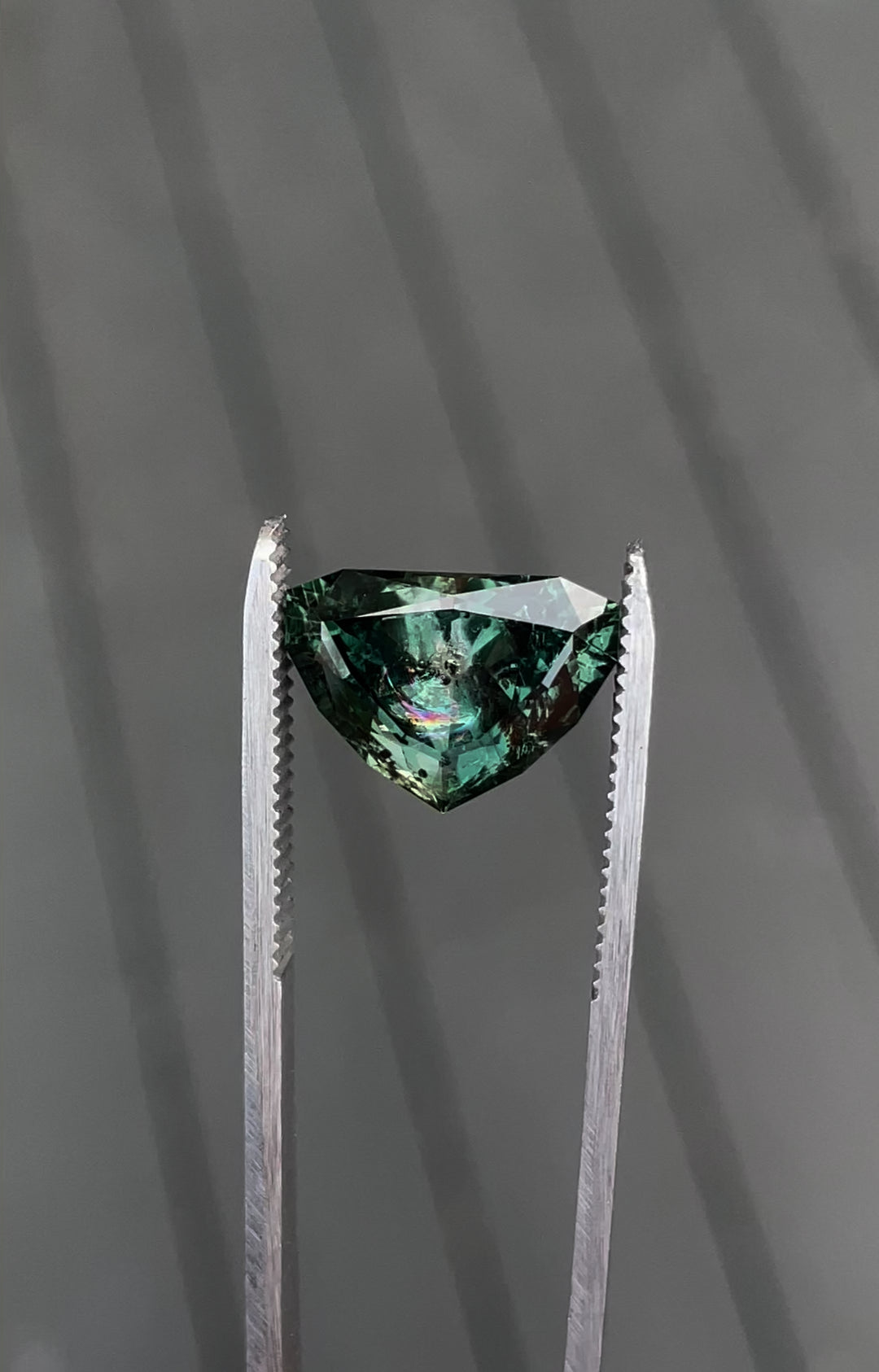A detailed view of a 7.06-carat sapphire with a bluish-green to gray-purple color change, featuring a modified shield brilliant cut, ethically sourced from Montana.