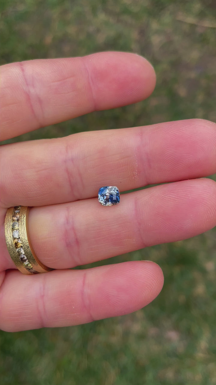 A 1.78-carat Madagascar Parti Sapphire rotating to reveal its modified brilliant cushion cut. The video captures the gemstone's vibrant mix of yellow, colorless, denim, and Ceylon blue hues as they shimmer under natural light.