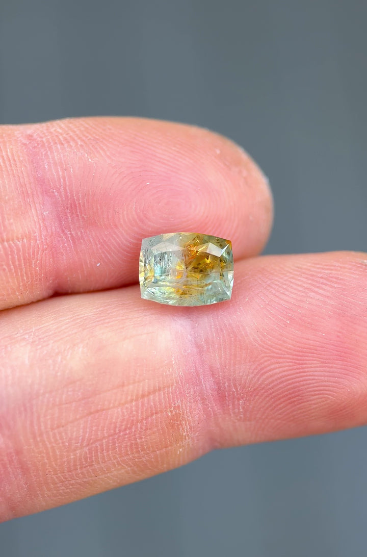 Handheld video of an unheated 2.99 carat Montana sapphire capturing the play of light across its orange and teal hues in a cushion-style cut.