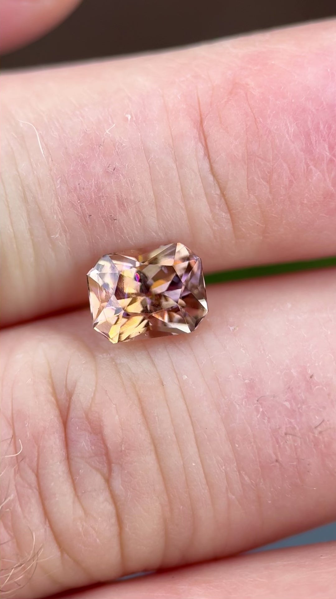 Rotating video of a 2.51 carat Tanzanite in radiant cut, capturing color shifts from peach and lavender to champagne and orange in natural light.