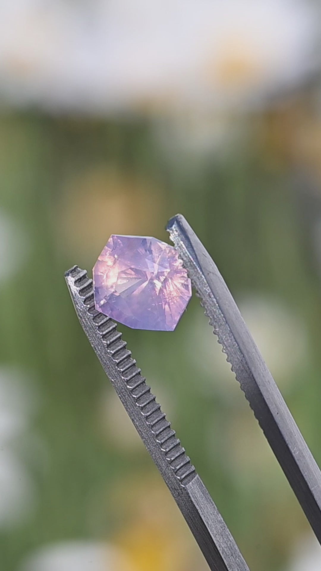 Rotating 3.43 carat opalescent lavender pink sapphire in tweezers showing color movement and custom geometric radiant cut from Sri Lanka.