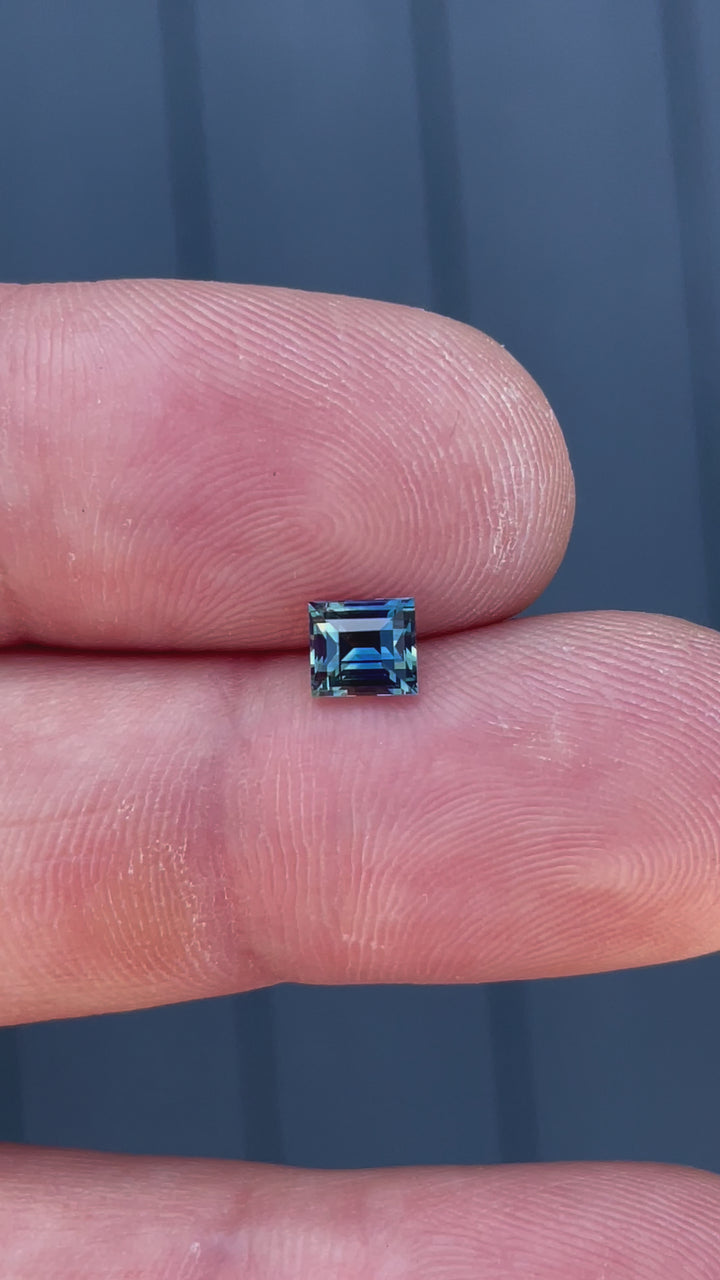 360-degree video of a natural bi-color sapphire in green and blue, capturing its brilliance in an antique Carre cut.