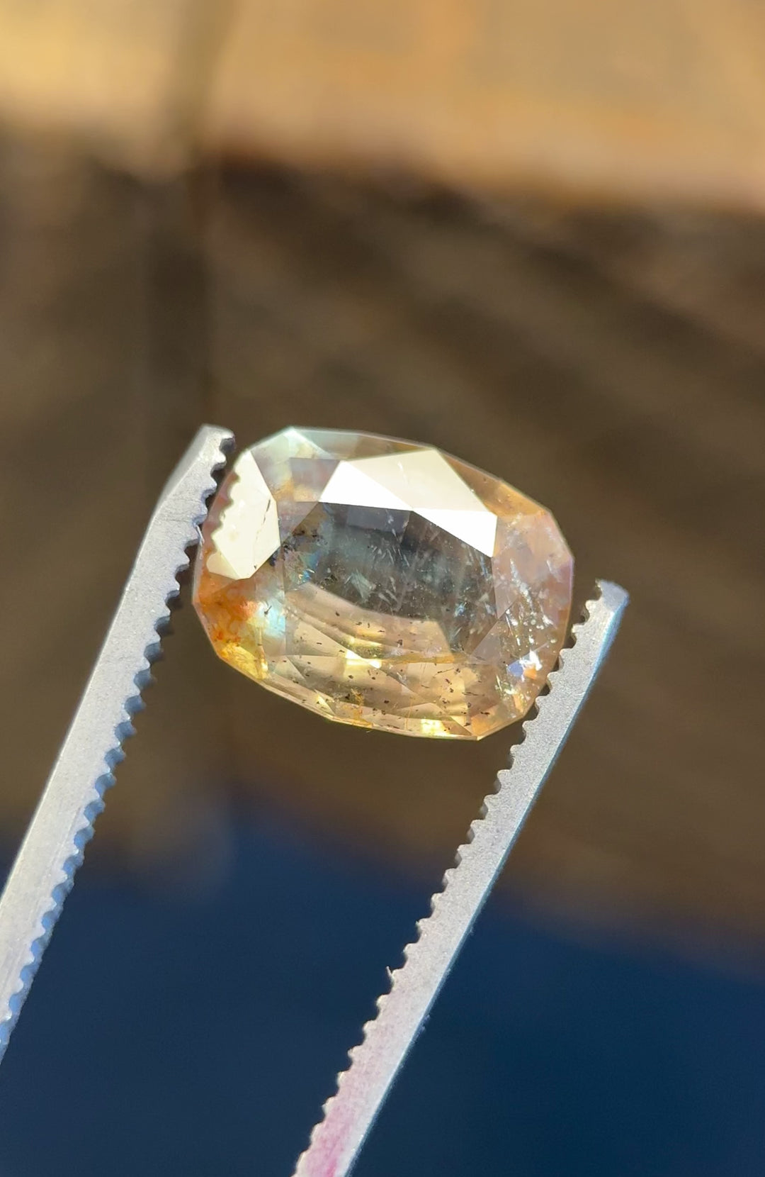 Rotating video of a 4.02ct antique-style cushion cut sapphire, showing vibrant earthy golden peach, pink, and green hues with visible inclusions and orange fluorescence under various lighting.
