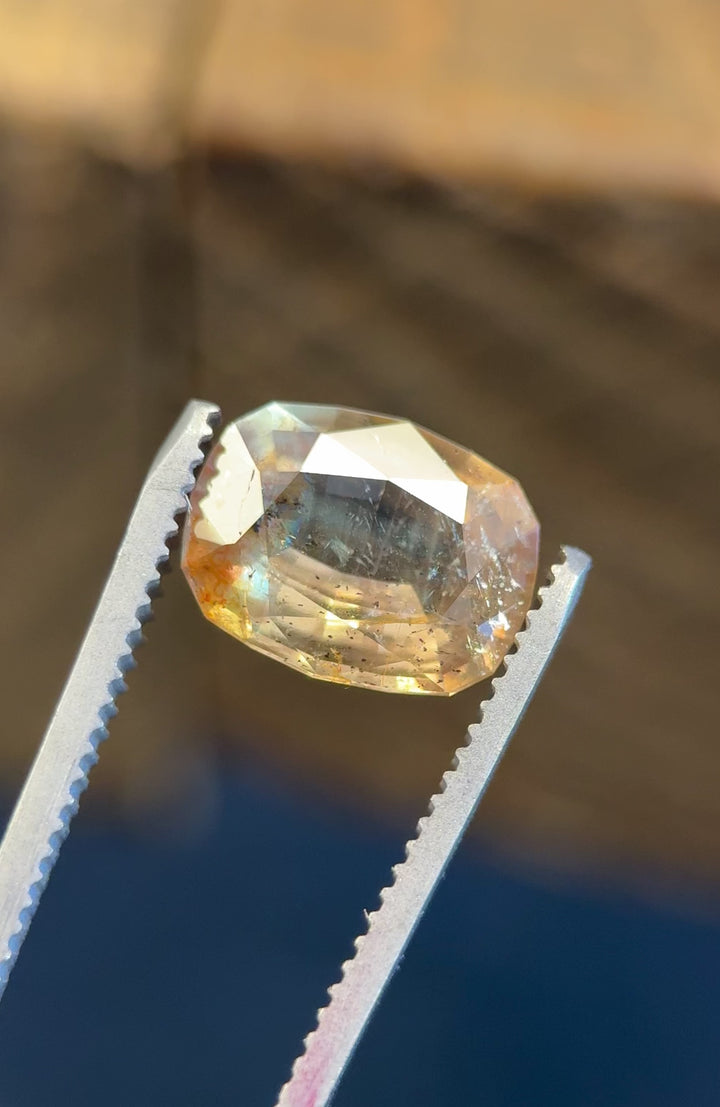 Rotating video of a 4.02ct antique-style cushion cut sapphire, showing vibrant earthy golden peach, pink, and green hues with visible inclusions and orange fluorescence under various lighting.
