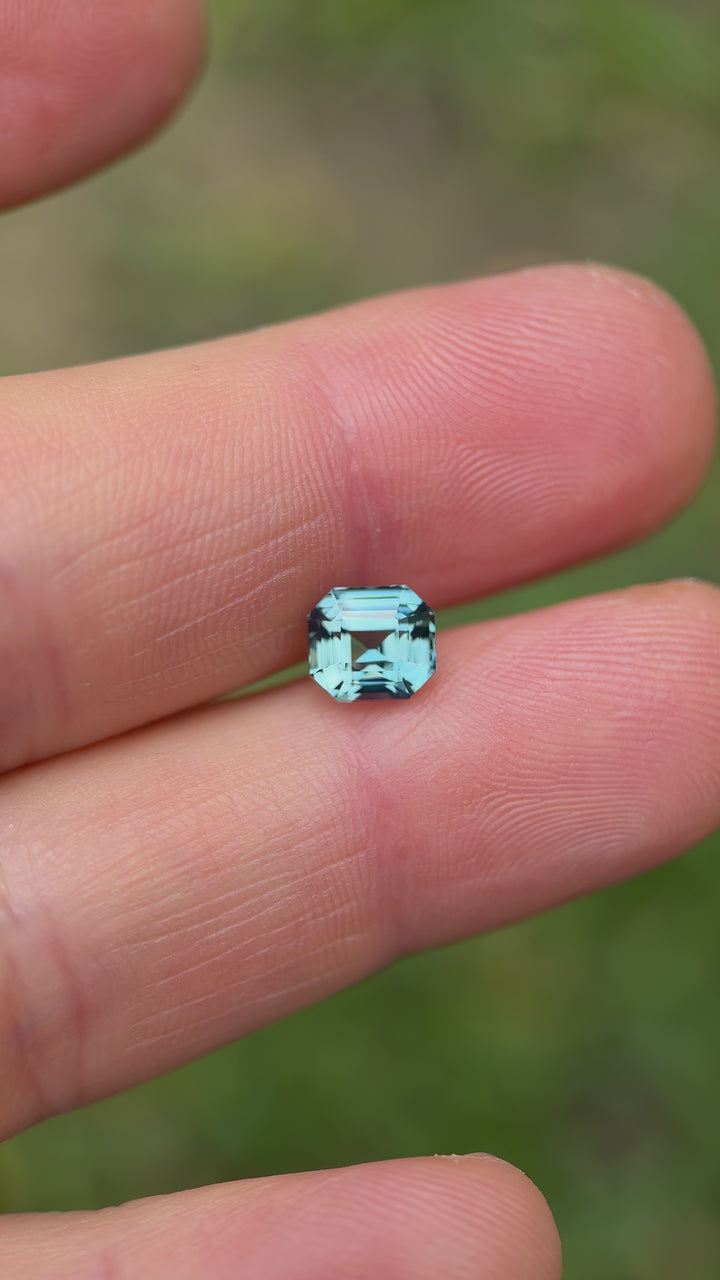 Macro video showcasing the clarity and depth of a 2.14-carat sky blue sapphire with an emerald cut, capturing its reflective luster from multiple angles.