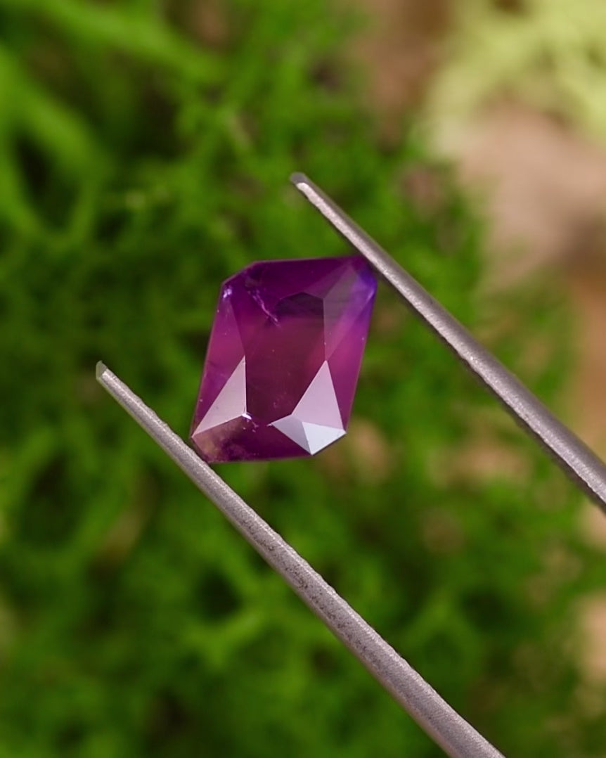 Video of 2.85CT pink, purple, and red sapphire rotating in tweezers under natural sunlight, revealing radiant emerald cut brilliance and color transitions in this unheated gemstone from Umba River Valley, Tanzania