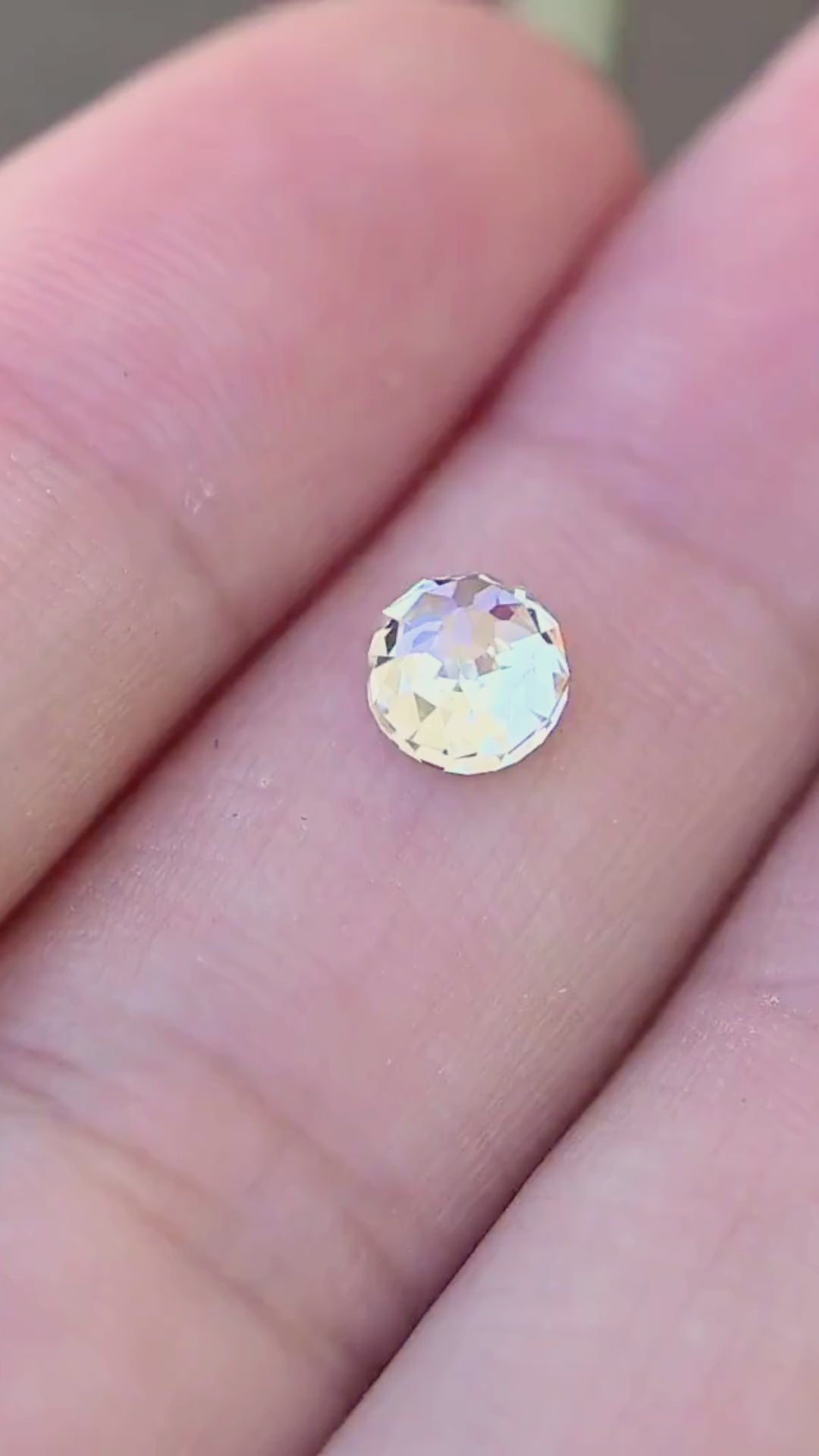 1.06 carat round Mughal cut South African diamond shown in motion on a hand, revealing its scale and shifting ivory, champagne and silvery reflections in natural light.
