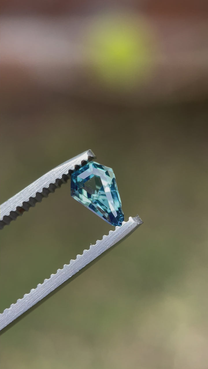 A video showcasing a 1.13-carat opalescent denim blue sapphire in motion, revealing the gem's step cut shield facets and brilliance as it is rotated. Captured to highlight the gem's exceptional quality and no-heat treatment.
