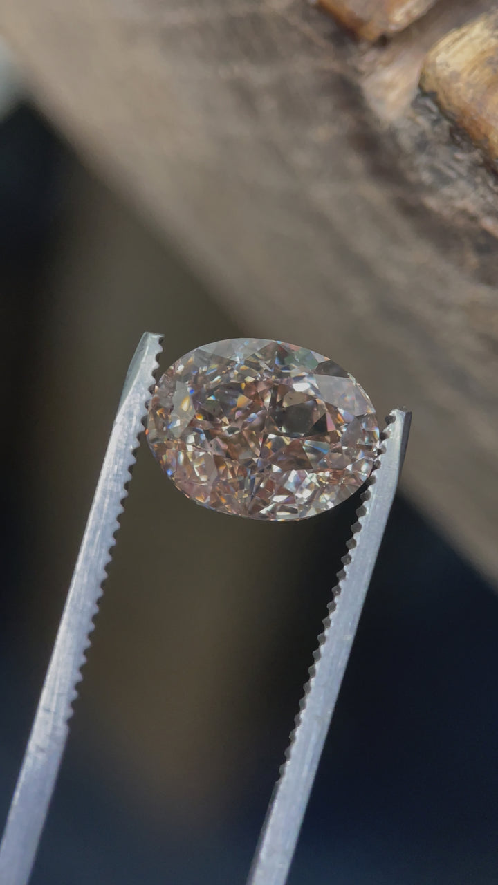 Macro video of a 5.25-carat oval brilliant diamond, highlighting its light champagne color, SI2 clarity, and excellent sparkle in a detailed close-up.