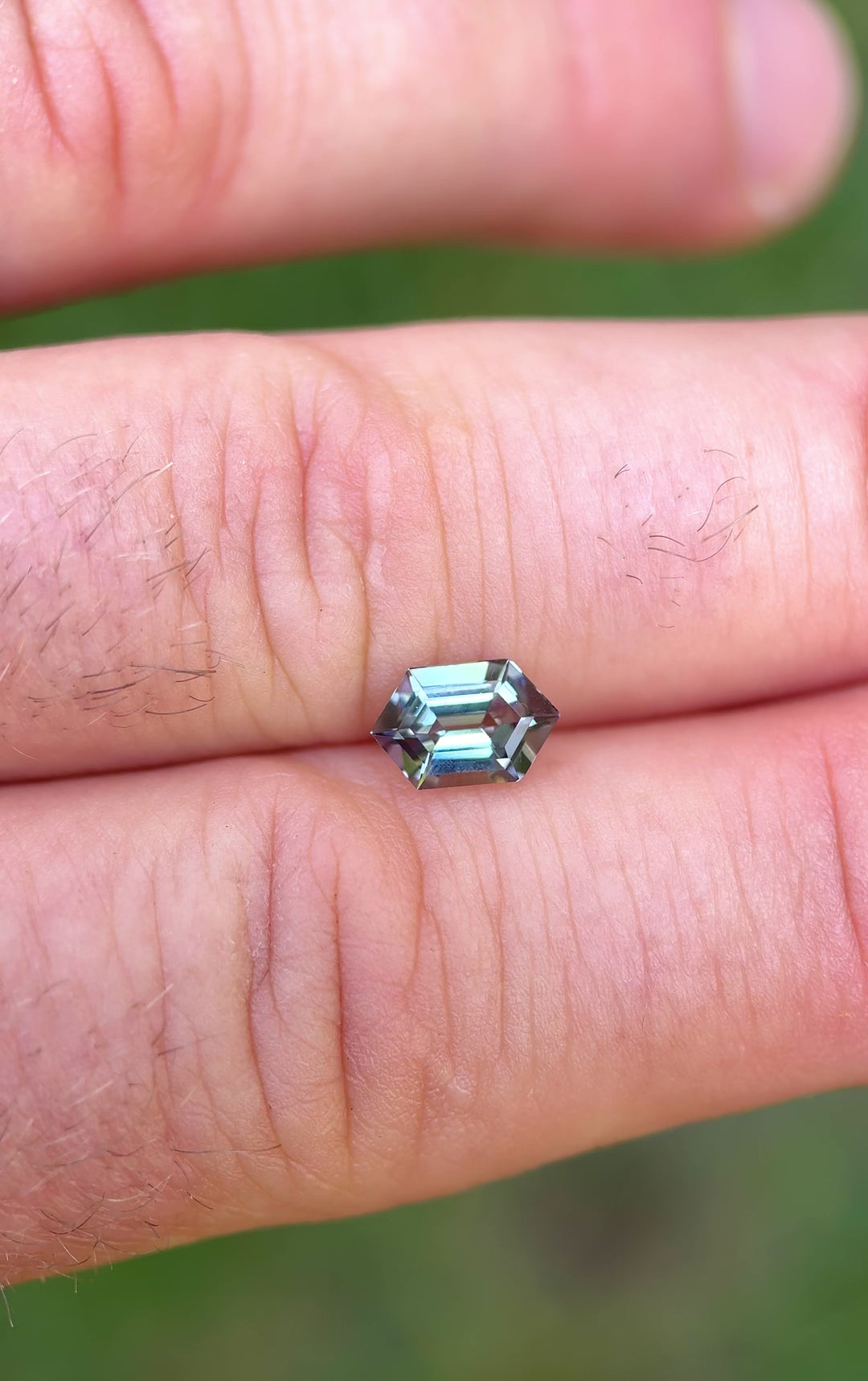 360-degree view of 1.14 carat Tanzanite gemstone on hand, capturing its mermaid color shift and step hexagon cut in natural lighting