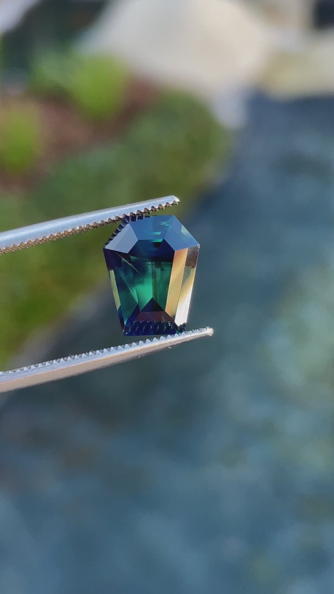  4.65-carat natural forest green and teal sapphire in a step cut coffin shape, highlighting its brilliance and color transitions as it moves under light.