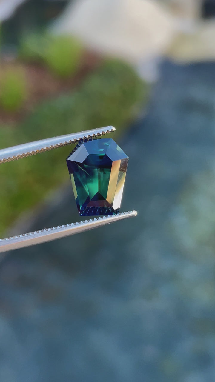  4.65-carat natural forest green and teal sapphire in a step cut coffin shape, highlighting its brilliance and color transitions as it moves under light.