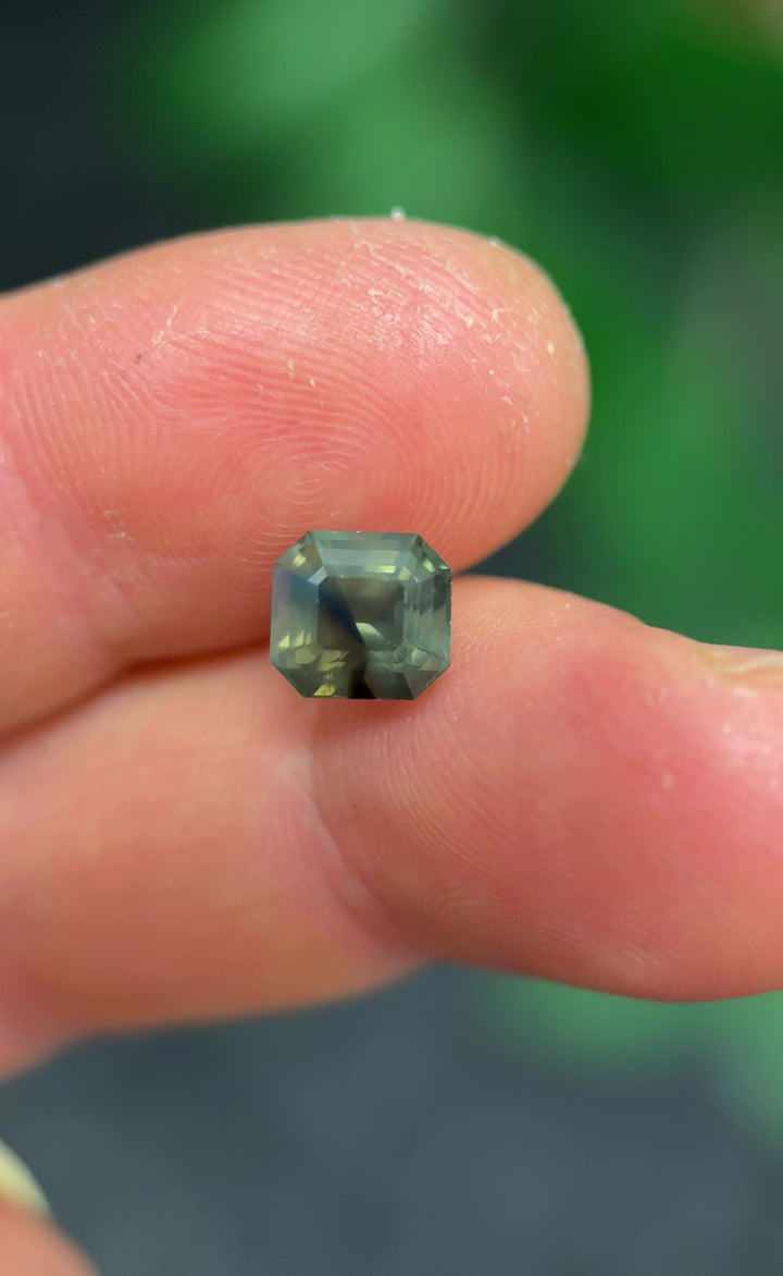 Side view video of an untreated 3.40 carat Nigerian sapphire, precision emerald cut showing depth, step facets, and opalescent olive blue color zoning