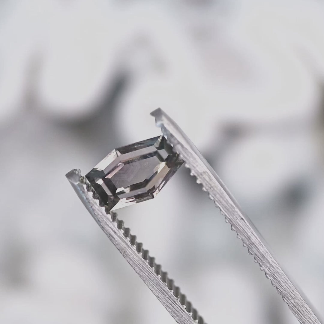 Close-up video of 1.15 carat purple pink gray Montana sapphire in tweezers, hexagon portrait cut showing sparkle, color zoning, and natural inclusions, untreated USA origin.