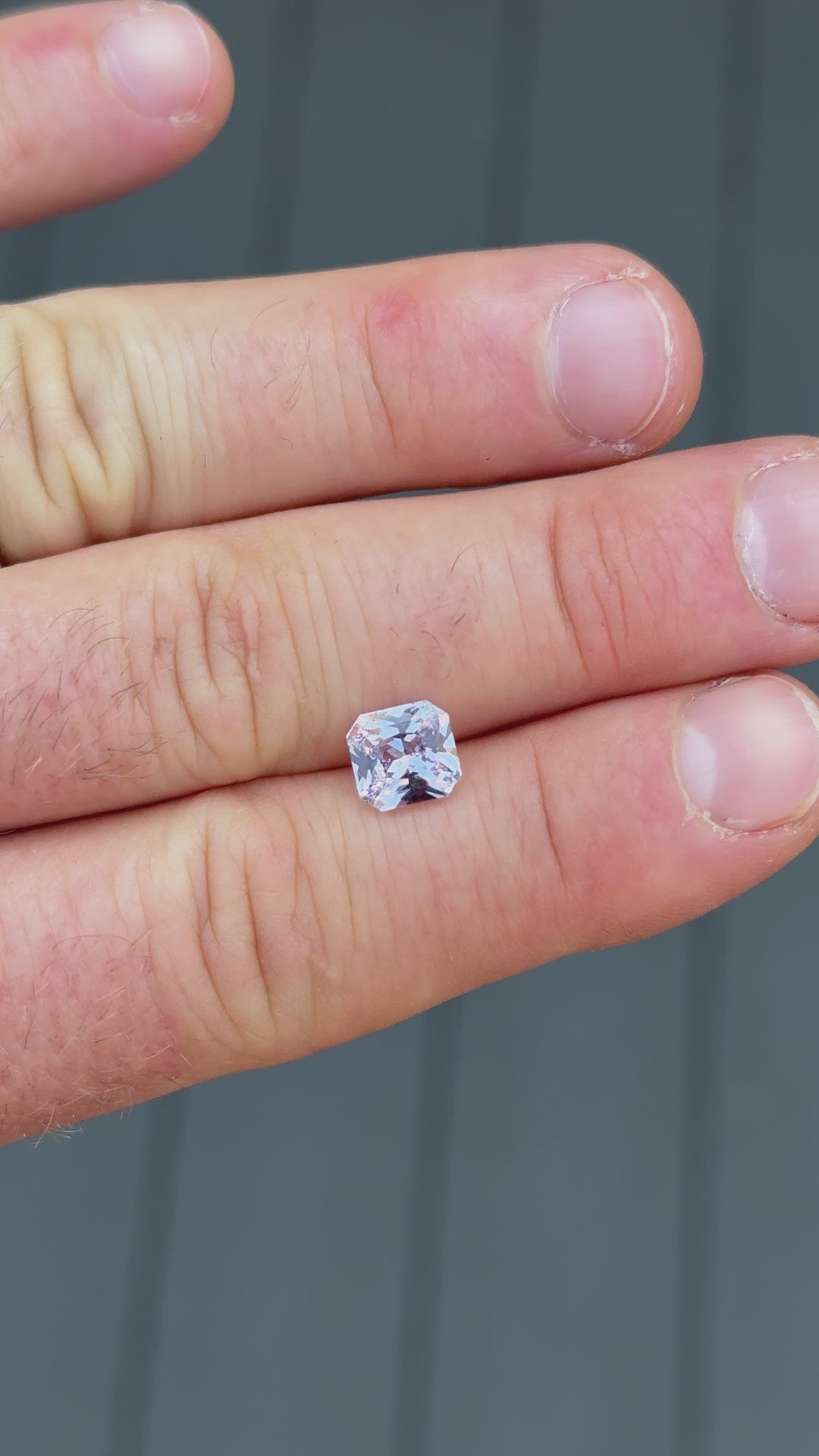 Macro video of a 2.14-carat untreated pastel sapphire being gently moved in tweezers, revealing the intricate play of lavender, pink, and purple tones with a soft neutral backdrop.