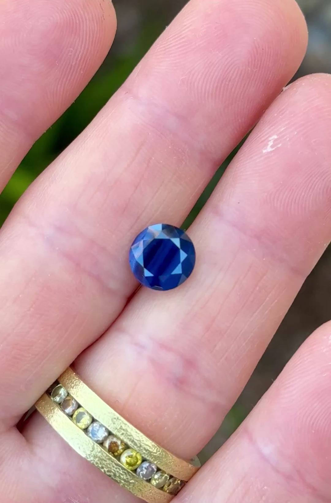 Opalescent blue sapphire rotating under light showing banded structure and soft glow across the stone.
