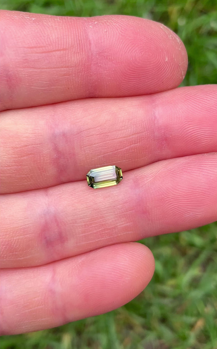 Natural lighting video of bi-color sapphire with emerald cut, highlighting untreated clarity and dynamic color shift from yellow to green