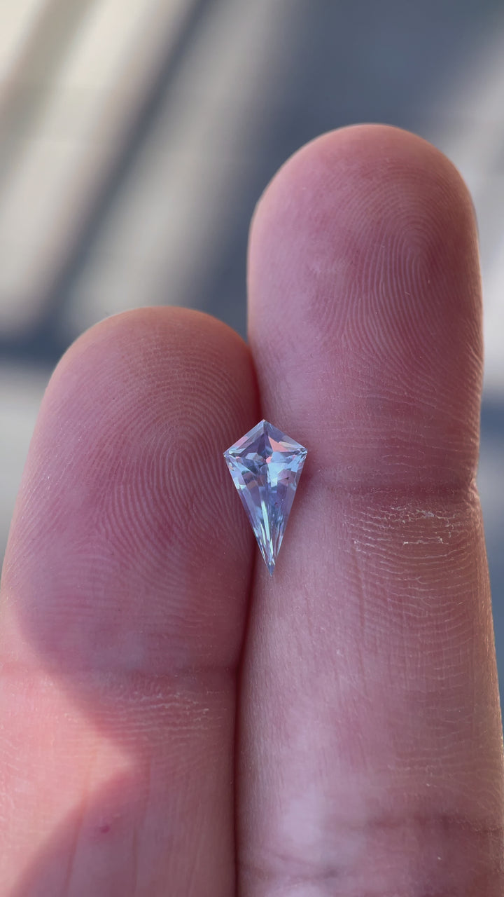 Detailed presentation of a 1.66 carat periwinkle sapphire, capturing the light play across its geometric step cut surfaces, highlighting its origin and natural beauty.