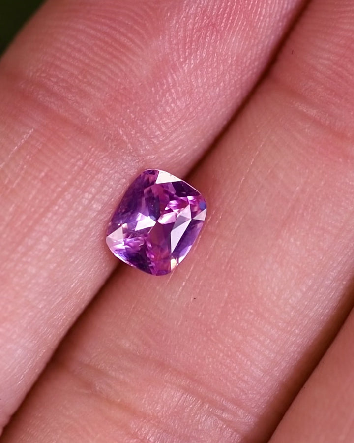 Close-up motion video showing 1.01 carat pink sapphire reflecting natural light from multiple angles, showcasing sparkle and fire of its cushion brilliant cut, unheated sapphire from Madagascar.