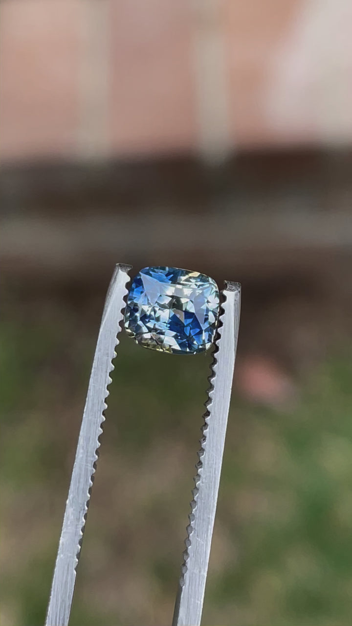 A close-up video of a 1.78-carat Madagascar Parti Sapphire, highlighting the intricate details of the cushion cut. The gemstone's unique color blend of yellow, blue, and colorless tones sparkles as it moves.
