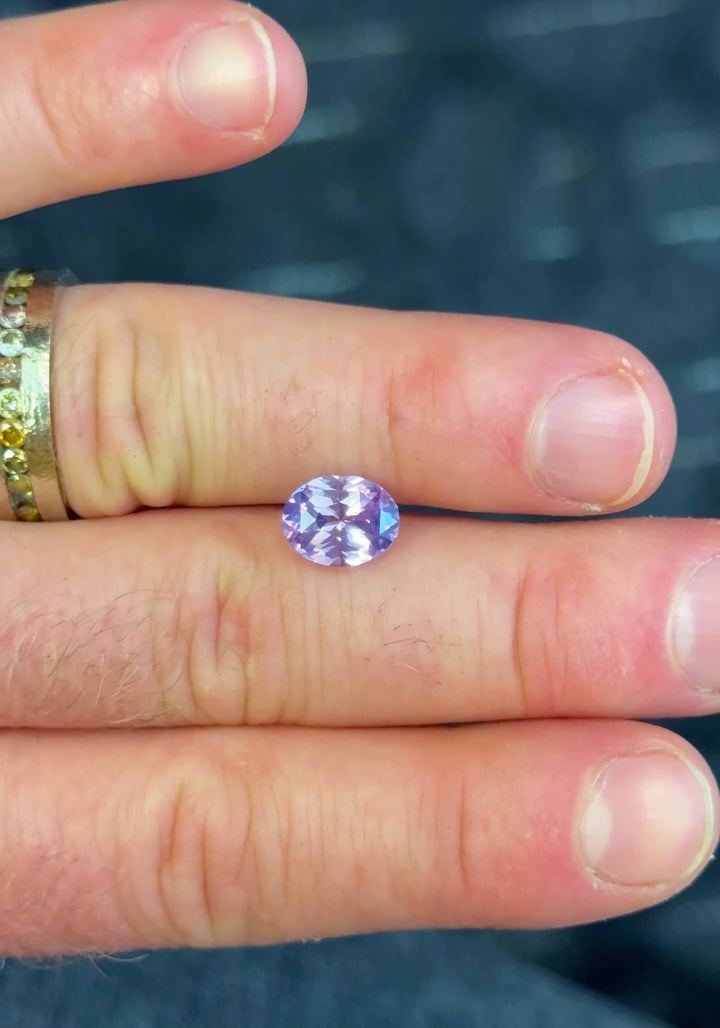 Close-up handheld video of untreated 4.04CT sapphire displaying color change between pink and violet tones as light shifts across the stone, ethically sourced from Madagascar.