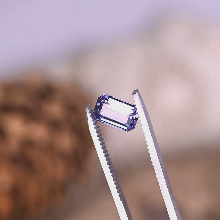 Close-up video of 2.08ct lavender purple Tanzanite octagonal step cut held in tweezers, precision faceted Tanzania gemstone displaying crisp beveled corners, clarity and strong geometric brilliance