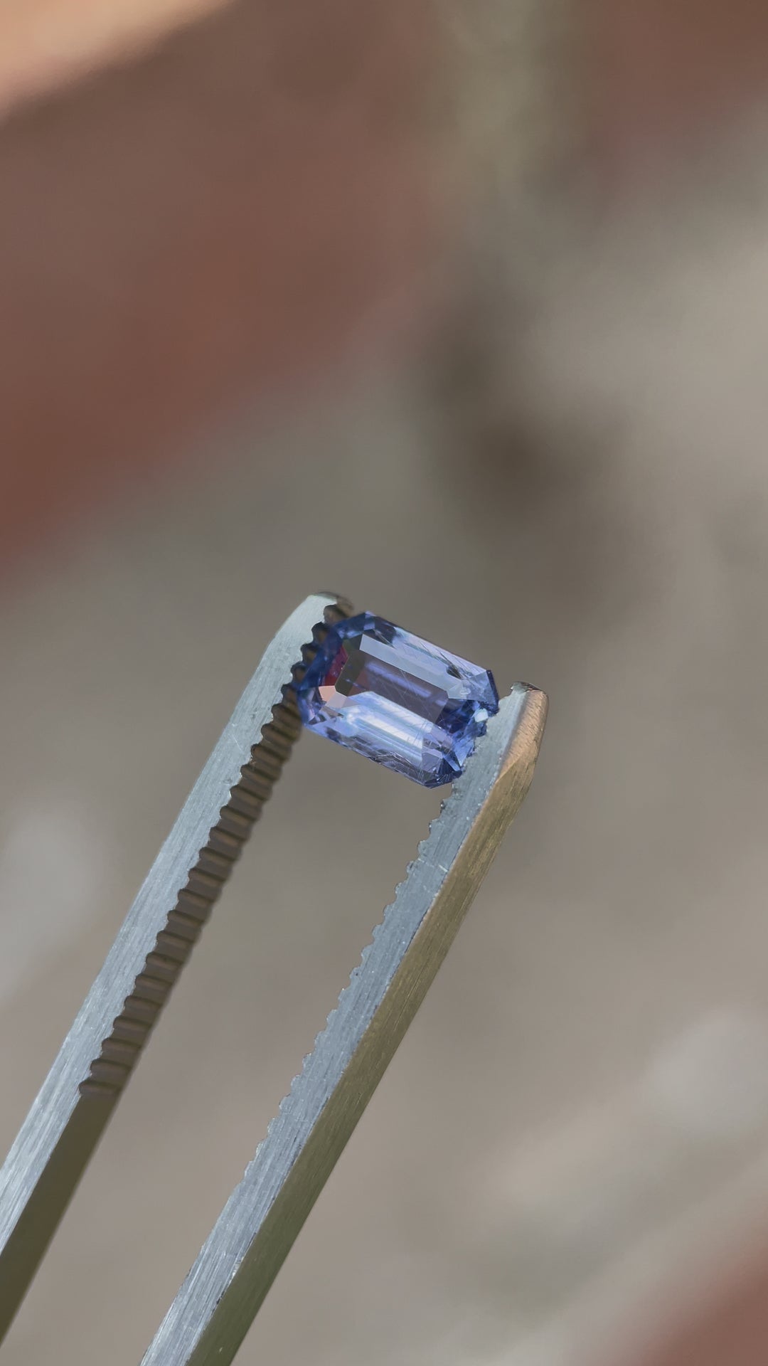 A video showcasing a 1.26-carat sapphire with violet-blue hues, cut in a Modified Emerald style, displayed under natural light to emphasize its brilliance.