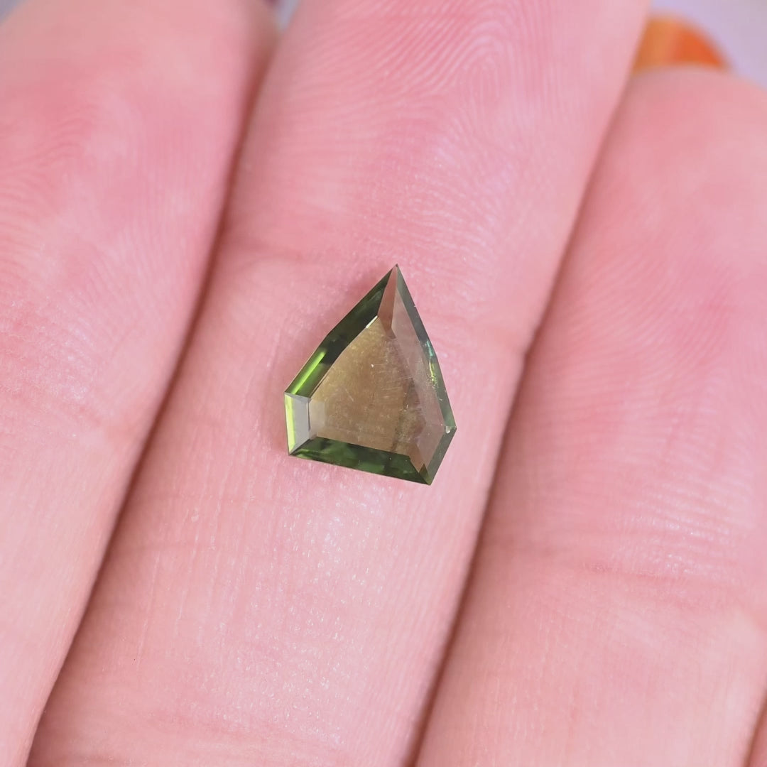 Rotating loose olive green sapphire from Gombe, Nigeria showing the clean lines of the custom shield portrait cut and subtle color shifts in light.