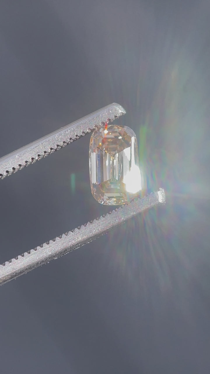 A stunning 1.03-carat champagne diamond with a light fancy yellowish brown hue, showcased in a close-up view to highlight its antique-style elongated step cut cushion shape.