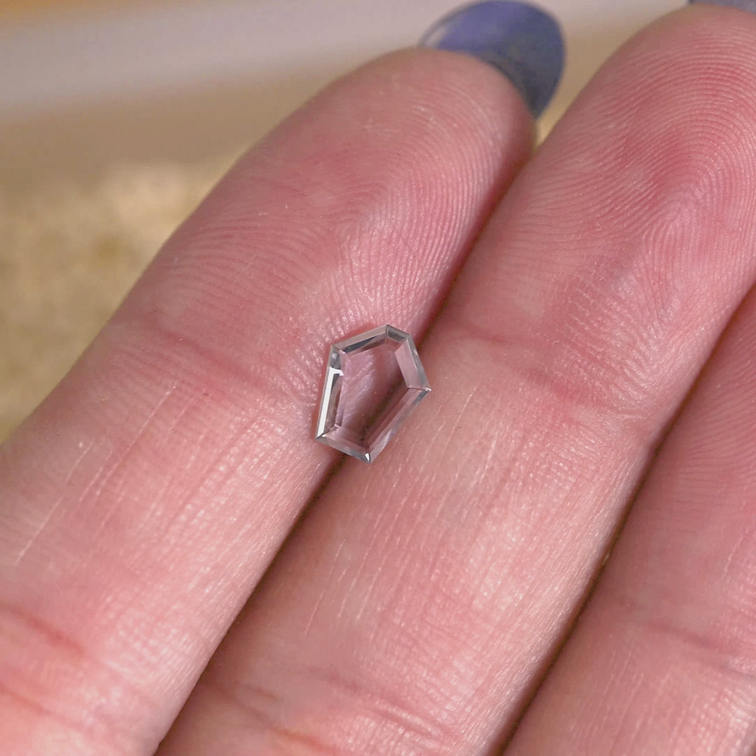 Rotating loose green, blue and teal Montana sapphire shown on hand, revealing the transparency and subtle color shift of the pentagon portrait cut.