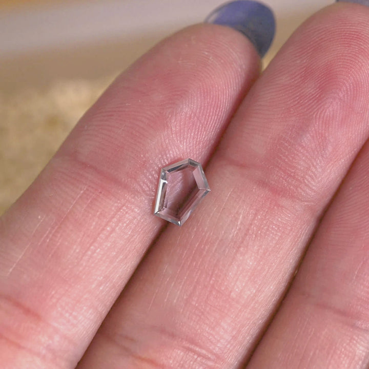 Rotating loose green, blue and teal Montana sapphire shown on hand, revealing the transparency and subtle color shift of the pentagon portrait cut.