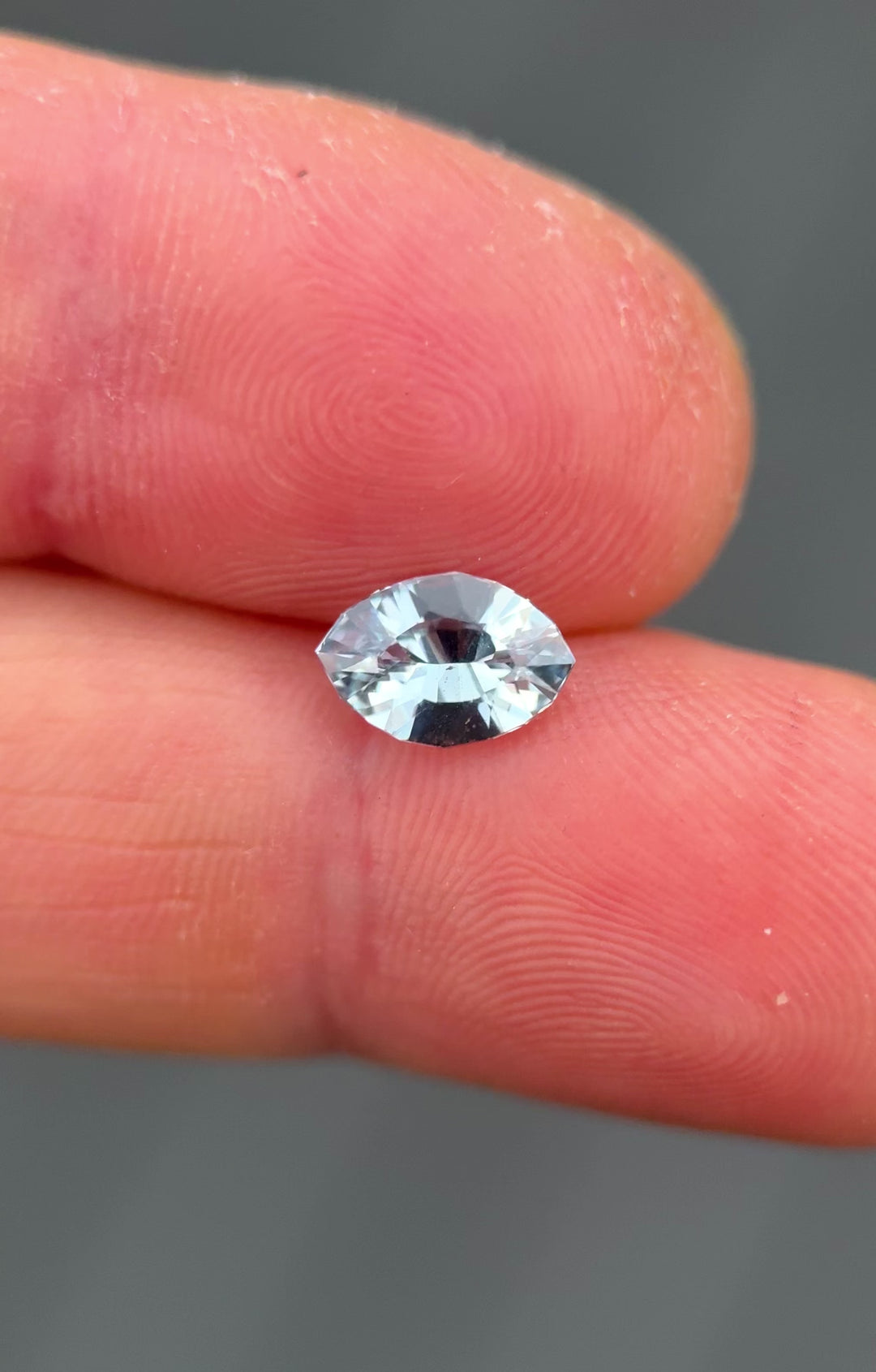 Close-up video of 1.58 carat teal blue green sapphire on fingertip, showcasing its lively sparkle, clarity, and shimmering hues in a precision marquise mixed cut, untreated sapphire from Sakaraha, Madagascar.