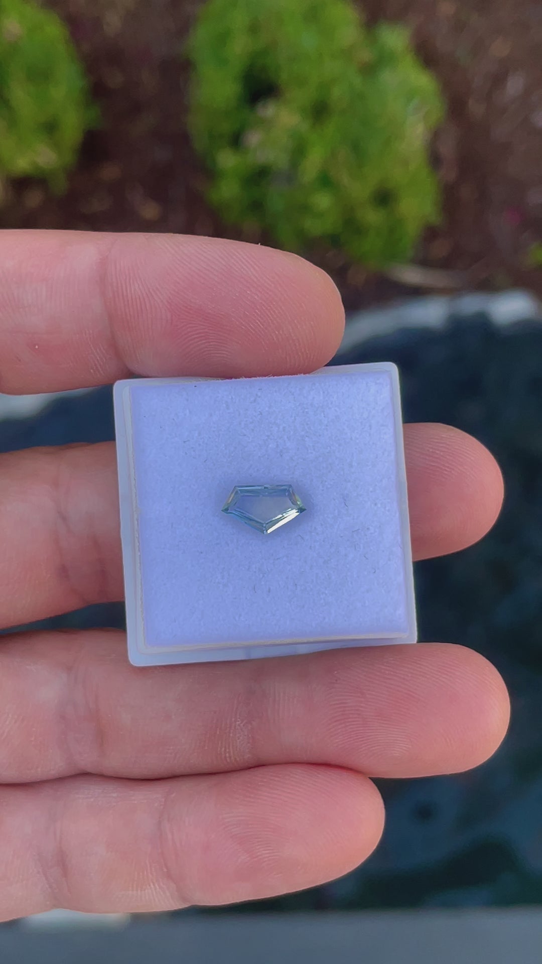 Close-up examination of a 1.20-carat Sri Lankan sapphire, revealing the intricate details and craftsmanship of the geometric step cut and its captivating color variations from yellow to cornflower blue.
