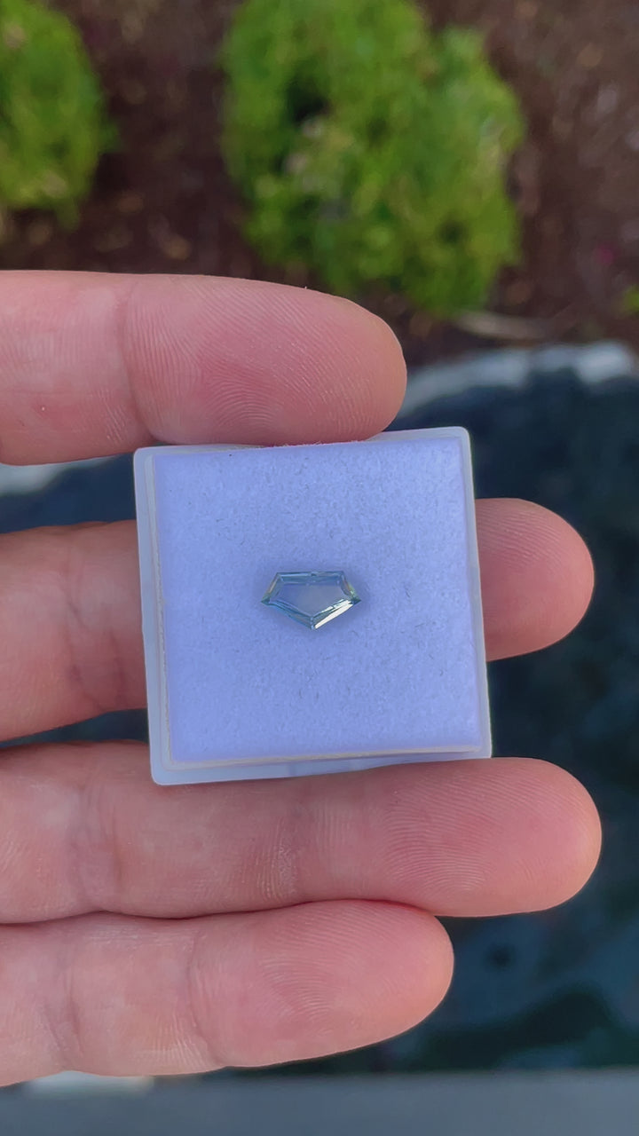 Close-up examination of a 1.20-carat Sri Lankan sapphire, revealing the intricate details and craftsmanship of the geometric step cut and its captivating color variations from yellow to cornflower blue.