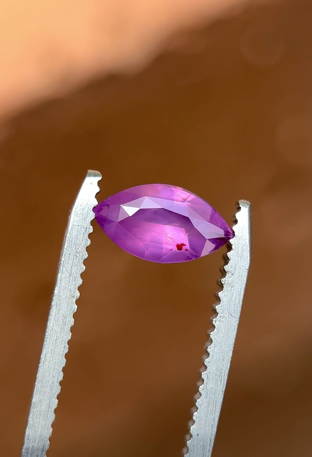 Video of untreated 1.15 carat sapphire from Sri Lanka rotating in tweezers, revealing opalescent pink and violet hues in marquise cut