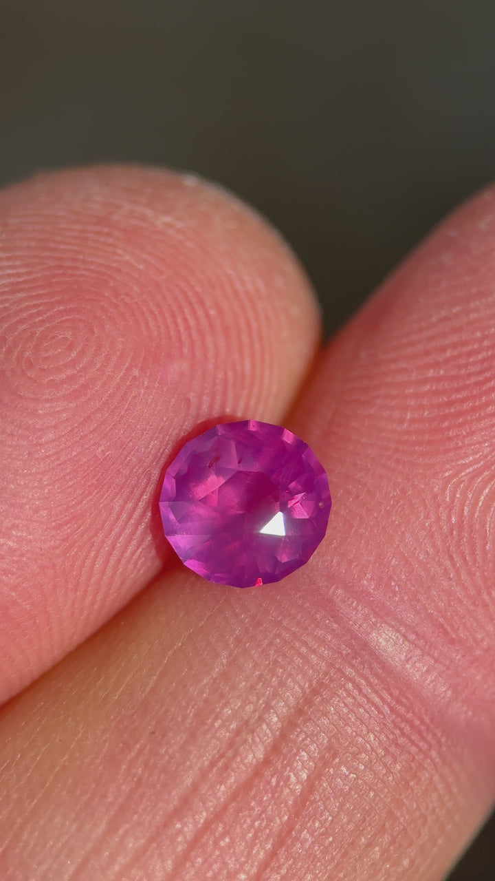 Rotating loose pink opalescent sapphire custom round cut from Sri Lanka revealing vibrant pink color and sparkle as the gemstone turns in the light.