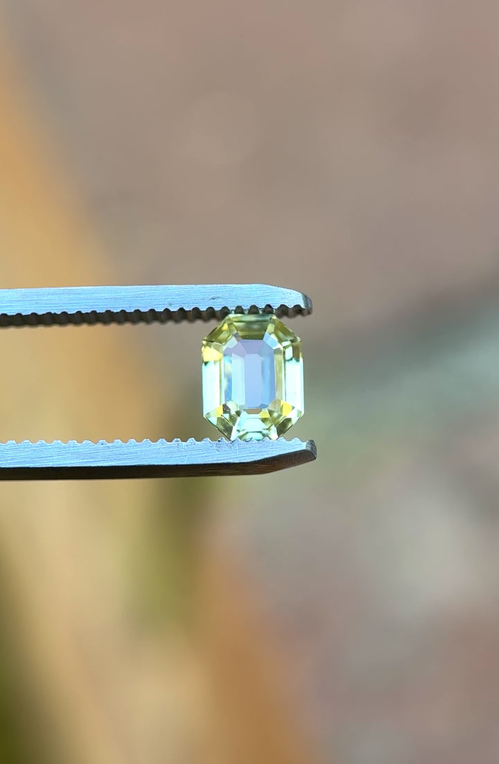 Video of 1.55CT yellow sapphire rotating in gemstone tweezers, capturing the gem’s bright golden sparkle and step-cut precision of the custom antidote emerald cut, unheated sapphire from Sakaraha, Madagascar.