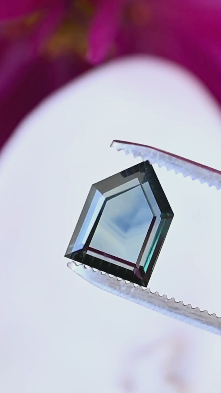 Explore the stepped edges, broad central facet and opalescent interior of this 3.68ct untreated sapphire from Gombe, Nigeria, in a close-up tweezer view.