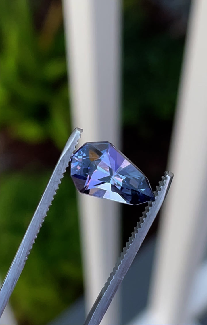 A stunning 3.31-carat tanzanite gemstone with a mix of gray, blue, and purple hues, expertly cut into a modified geometric pear shape, originating from Merelani Hills, Tanzania.