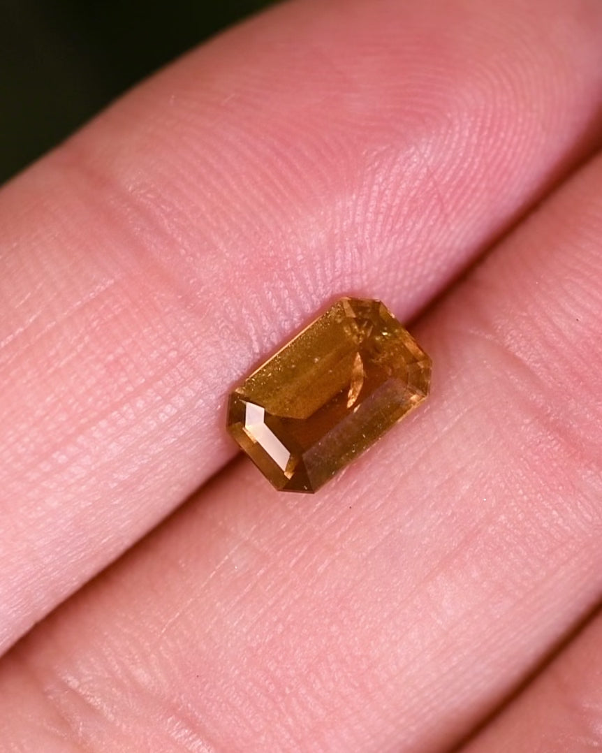 Macro video of 1.57 carat brown yellow sapphire turning slowly, revealing light reflections and depth through its modified emerald cut, untreated sapphire from Umba River Valley, Tanga, Tanzania.