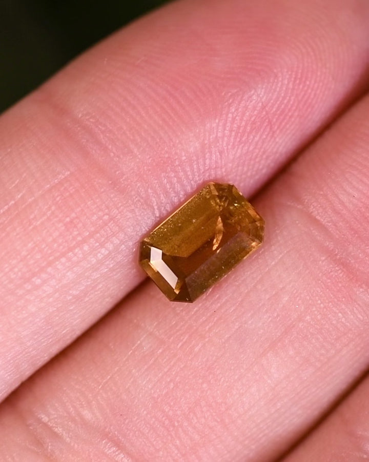 Macro video of 1.57 carat brown yellow sapphire turning slowly, revealing light reflections and depth through its modified emerald cut, untreated sapphire from Umba River Valley, Tanga, Tanzania.
