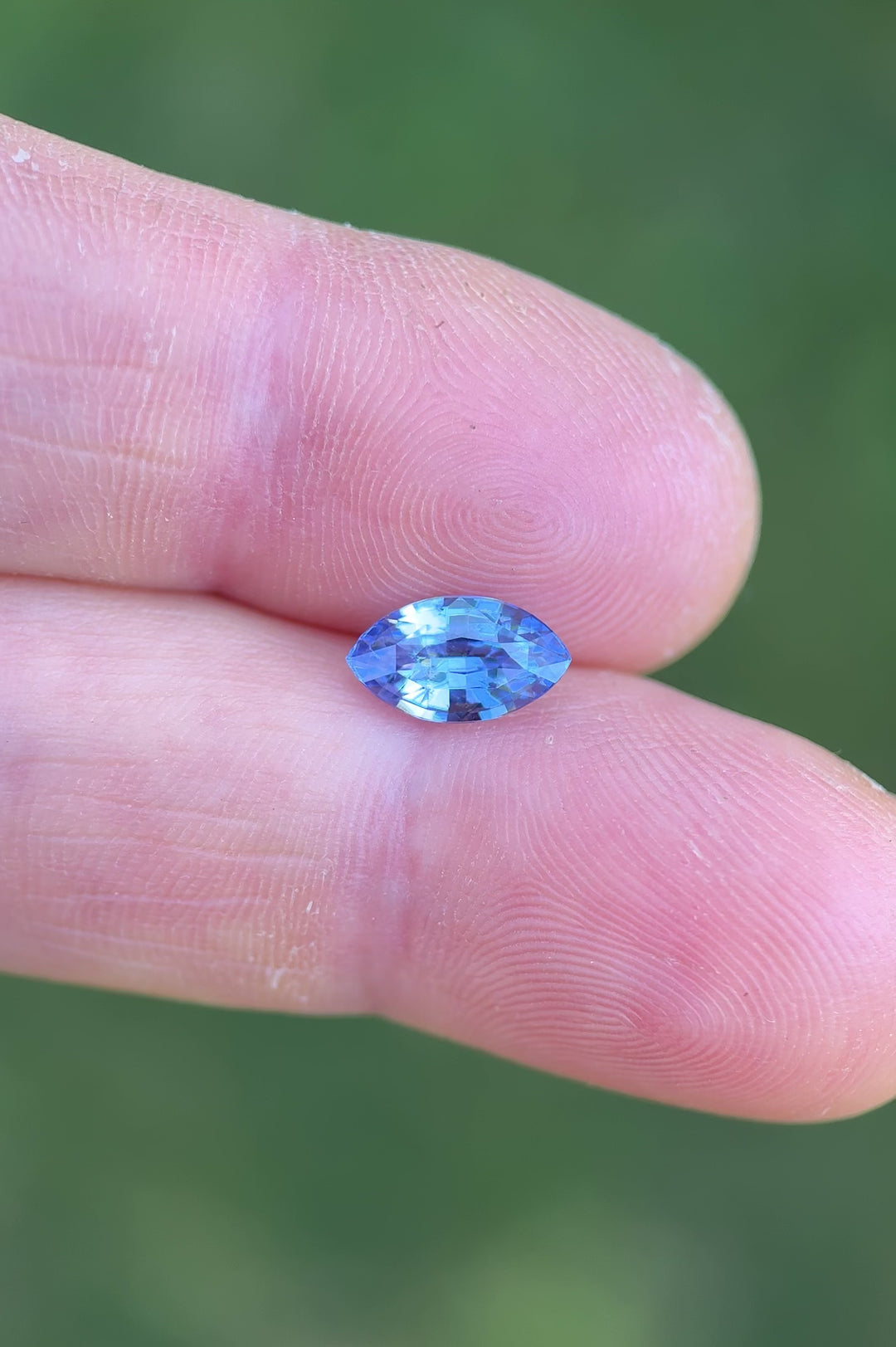 Handheld video of natural 1.70 carat cornflower blue violet sapphire reflecting light across marquise mixed cut facets, untreated gem from Madagascar showing clarity and brilliance.