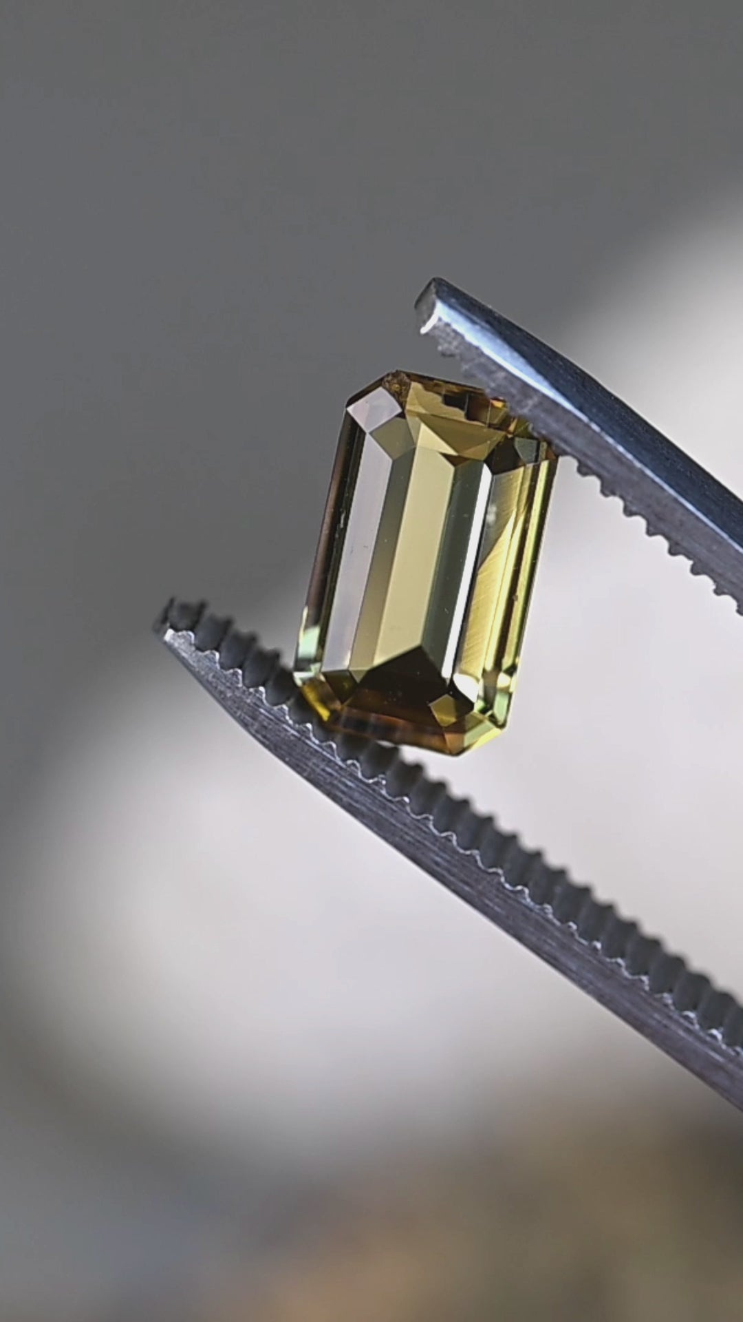 Watch this rare untreated 2.06 carat yellow-green tanzanite reveal its remarkable pleochroic shifts between golden yellow and olive green through a precision geometric cut.