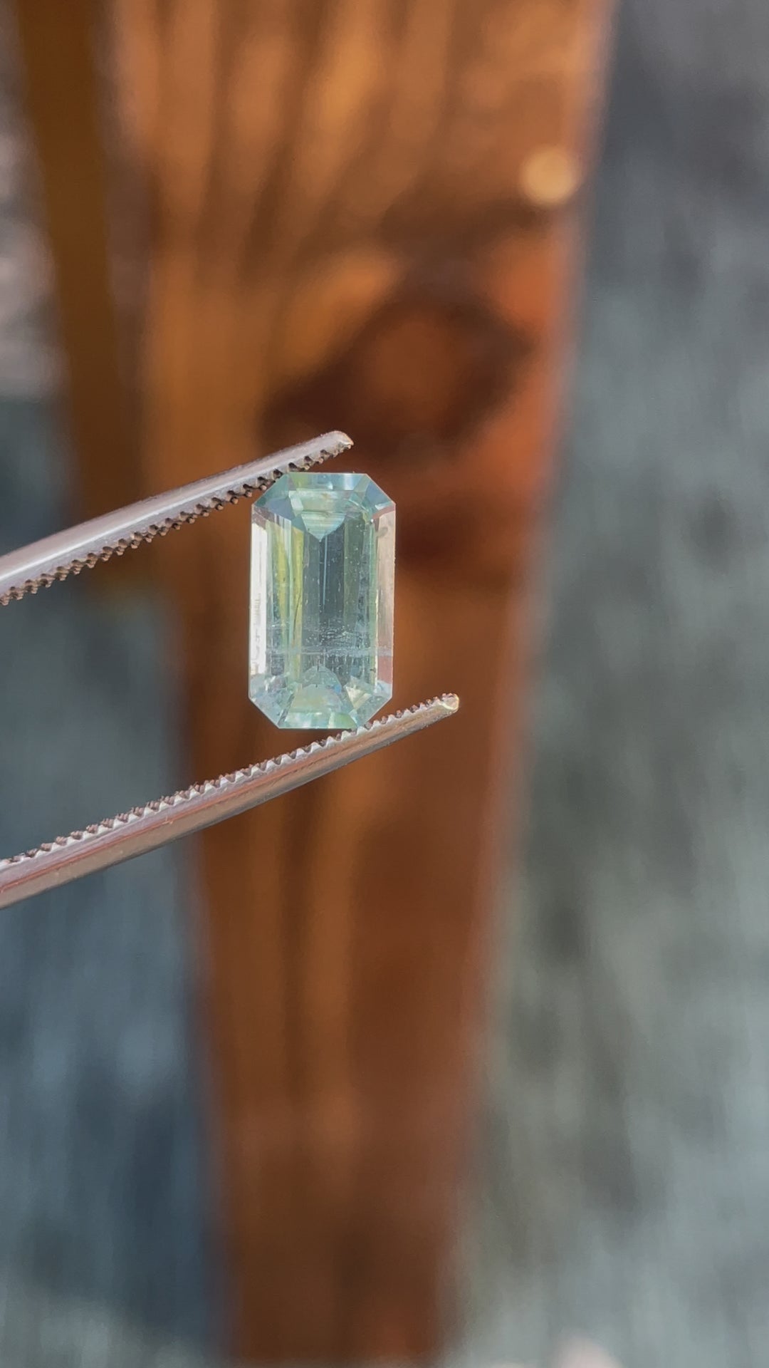 Close-up video of a 1.72-carat emerald-cut aquamarine gemstone with green, seafoam, and blue hues, originating from Nasarawa, Nigeria.